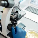 Ερευνητής εξετάζει βιολογικό δείγμα με μικροσκόπιο σε εργαστήριο